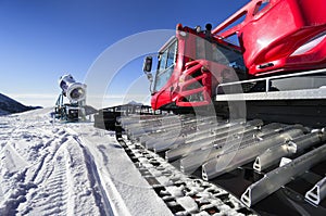 Snowmaking gun and snow groomer on ski slopes