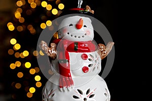 Snowman ceramic figurine decoration with Christmas tree lights bokeh.