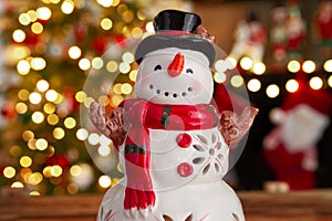 Snowman ceramic figurine decoration with Christmas tree lights bokeh.
