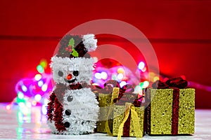 Snowman Christmas figurine near glittery gifts isolated on blurred background of lights. Christmas decorations isolated
