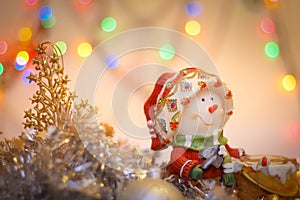 Snowman close-up on the background of blurry colored lights tinsel and Happy New Year