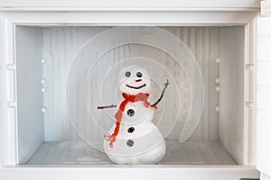 Snowman in empty freezer. Buildup of ice, cleaning and servicing concept. Funny diet idea