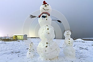 Snowman family on the meadow at night