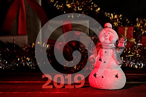 Snowman and figures 2019 in the foreground and New Year`s decorations on a brown wooden background. new Year. Christmas. holidays