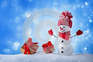 Snowman and gift boxes in winter snowy background. Christmas or New year greeting card