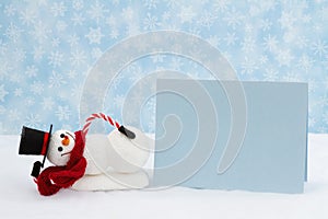 Snowman with hat and scarf and blank greeting card with snowflakes