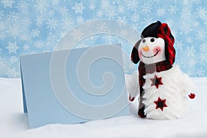 Snowman with hat and scarf and blank greeting card with snowflakes