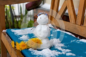 A snowman made of snow in summer on the green grass.