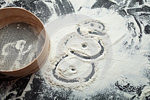 Snowman painted on a flour on a black background. Festive and Christmas baking