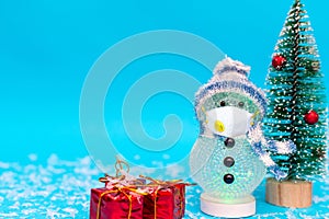 Snowman with protective mask presents and Christmas tree snow with copy space.new year celebration