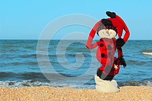 Snowman In Red Clothes Standing On The Beach.