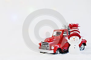 Snowman in a red hat near red christmas truck pickup, on a white background. christmas pickup. Merry christmas and happy new year