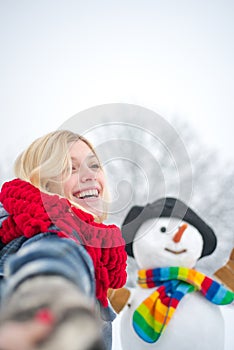 Snowman in snow forest. People in snow. Snowman and snow day. Winter portrait of young woman in the winter snowy scenery