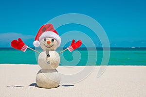 Snowman. Snowman with red Santa Claus hat and mittens. Merry Christmas and Happy New Year. Sandy Snowman on the beach