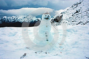 Snowman on top of a white snowy mountain with winter landscape