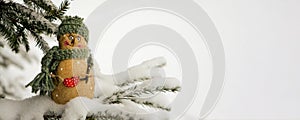 Snowman, toy on the background of a snowy Christmas tree. Snowing. Selective focus, blurred winter background. The concept of the