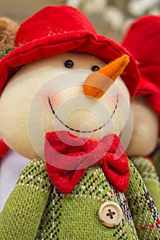 Snowman toy with red santa hat and carrot nose. Cute smiling snowman doll. Merry Christmas card concept. Winter fun and joy.
