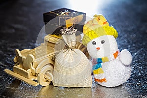 Snowman with wooden car, gift box and sack