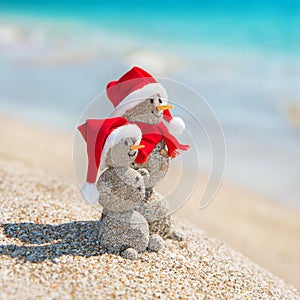 Snowmans couple at sea beach in christmas hat. New years holiday