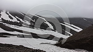 Snowmelt lies on the rocky mountain slopes.