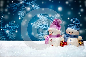 Snowmen dolls on blue winter background