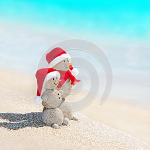 Snowmen friends at sea beach in christmas hat.