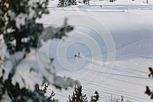 The snowmobile climbs up the slope of the mountain through an snow field