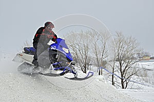 On the snowmobile rider jumps down the mountain