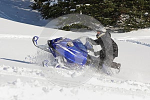 Snowmobile riderracing through snow in mountains