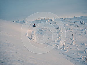 Snowmobile on snowfield. Winter sport. Snowcapped mountains and cloudy weather with blizzard in Khibiny Mountains, Russia