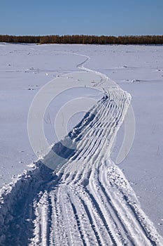 Snowmobile trail on a snowy plain.