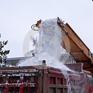 Snowplow cleans the city after a snow storm. Close-up. Snow plow tractor and truck work on the street. Municipal urban road