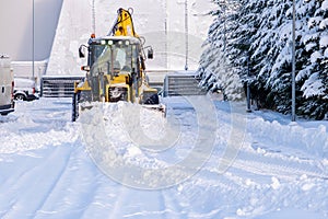 Snowplow plowing road during storm. Winter snow removal yellow large tractor