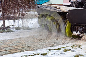 A snowplow removes snow from the sidewalk in the courtyard of a residential building