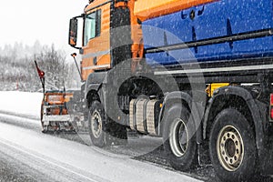 Snowplow truck removing dirty snow from city street or highway after heavy snowfalls. Traffic road situation. Weather