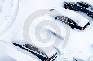 After a snowstorm, cars in the parking lot are covered with a th