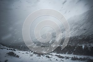 snowstorm with snowflakes swirling, obscuring the view of a mountain range