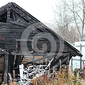 Snowy abandoned burned-out fire wooden black house.