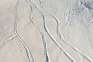 Snowy abstract off-piste skiing backround with ski and snowboard trails and tracks on new virgin powder snow. morning