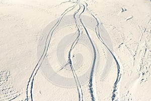 Snowy abstract off-piste skiing backround with ski and snowboard trails and tracks on new virgin powder snow. morning sunrise or