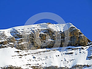 Snowy alpine mountain peak Sommet des Diablerets in the Les Diablerets massif seen from the Les Diablerets settlement - Suisse