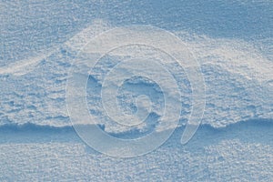 Snowy background, snow-covered surface of the earth after a blizzard in the morning in the sunlight with distinct layers of snow