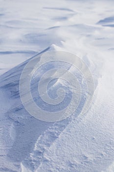 Snowy background, snow-covered surface of the earth after a blizzard in the morning in the sunlight with distinct layers of snow