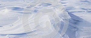 Snowy background, snow-covered surface of the earth after a blizzard in the morning in the sunlight with distinct layers of snow