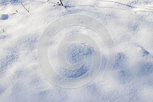 Snowy background, snowy surface with a clearly expressed texture of snow in the morning sun