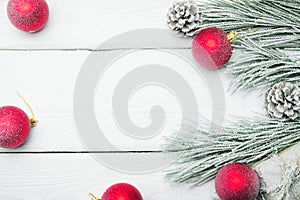 Snowy branch christmas tree and cone and red ball on white wooden vintage background