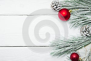 Snowy branch christmas tree and cone and red ball on white wooden vintage background