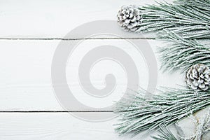 Snowy branch christmas tree and cone on white wooden vintage background