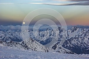 Snowy Caucasus mountains at sunset with moonrising and Anticrepuscular rays