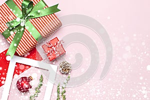 Snowy Christmas composition. White photo frame, red envelope, fir branches, cones ball twine gift wooden toys on pink background